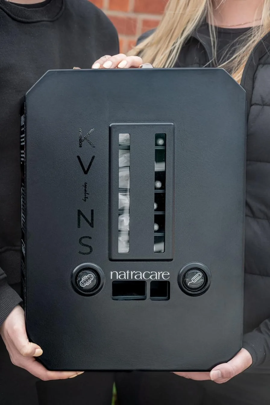 Kvins mensskyddsdispenser i svart metall med två fack för bindor och tamponger